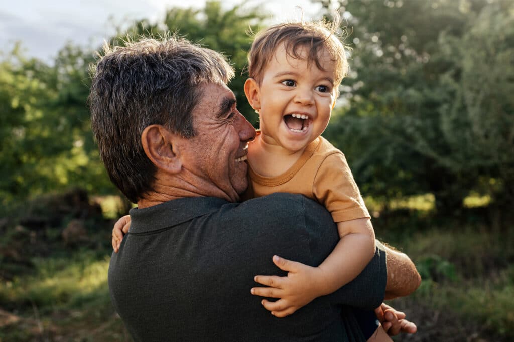 playful grandfather spending time with his grandson in park on sunny day